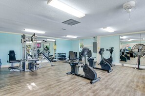 A gym with exercise equipment, a mirror, and a fan. - Beautiful condo with furnished balcony, pools, tennis, volleyball & fitness room (Hilton Head)