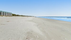 Ein Strand mit einem Hotel im Hintergrund.