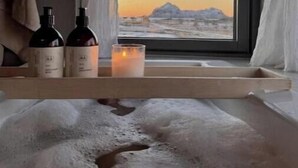 A room with a window, a bed, a bedside table with bottles and a candle. - Privat lodge, high-end (Nordland)