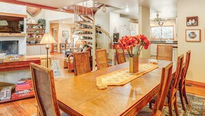 A dining area with a wooden table, chairs, a vase with flowers, a spiral staircase, and a bookshelf. - 2-story house with private heated outdoor pool, stunning views & foosball (Hilton Head)