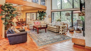 A spacious living room with a high ceiling, large windows, and a variety of seating arrangements. - 2-story house with private heated outdoor pool, stunning views & foosball (Hilton Head)