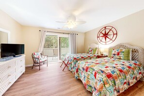 A bedroom with a bed, a television, a chair, a ceiling fan, and a window. - Bright & Beachy Dog Friendly Villa with Shared Pool (Hilton Head)
