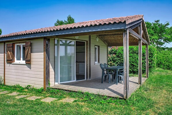 Ein kleines Holzhaus mit Terrasse, Schiebetüren und einem Tisch mit Stühlen.