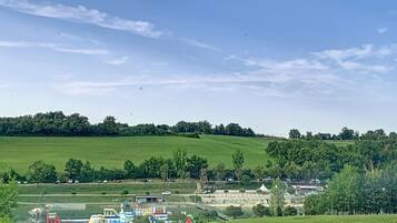 Paesaggio rurale con un prato verde, un piccolo edificio e una distesa d'acqua con strutture gonfiabili.
