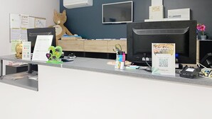 A reception desk with a large plush toy, a flat-screen TV, and a sign welcoming guests. - Monclar Escape With Tennis & Shared Pool (Monclar-de-Quercy)