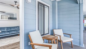 Ett rum med en blå yttervägg, en takfläkt i trä, en vit soffa och två vita stolar samt ett bord i trä.