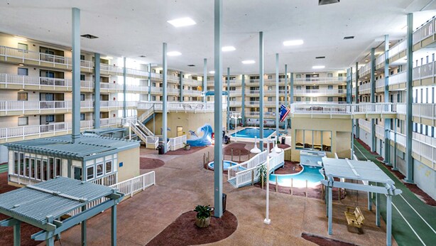 En anläggning med flera våningar och inomhusutrymmen, med ett centralt poolområde, flera balkonger och en mängd olika sittplatser och utrymmen för rekreation.