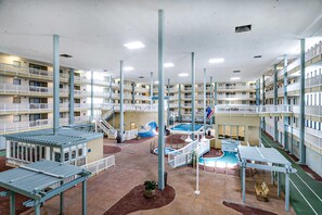 A multi-level indoor facility with a central pool area, multiple balconies, and a variety of seating and recreational spaces. - Updated getaway with pools, hot tub, close to beach (Hilton Head)