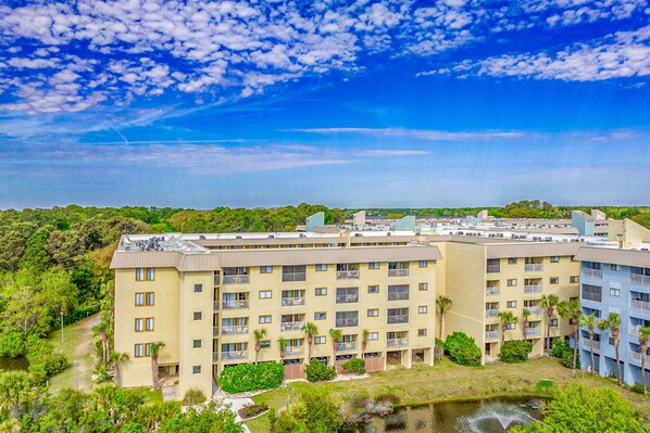 A multi-story hotel with balconies, a courtyard, and a view of the surrounding greenery. - Updated getaway with pools, hot tub, close to beach (Hilton Head)