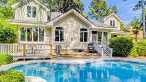 A large house with a swimming pool, a covered patio, and a staircase leading to the main entrance. - Bright & Expansive Beach Retreat with Private Pool (Hilton Head)