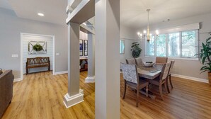 A spacious living room with hardwood floors, a bench, and a dining area with a table and chairs. - Bright & Expansive Beach Retreat with Private Pool (Hilton Head)
