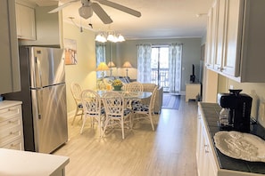 A kitchen with a stainless steel refrigerator, a dining table with chairs, and a ceiling fan. - 1st floor condo with  balcony, pools, tennis & close to beach (Hilton Head)