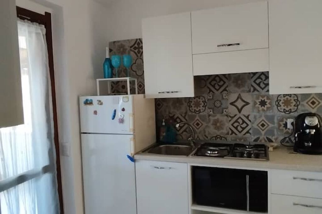 Una cocina con armarios blancos, un refrigerador, una estufa y un lavamanos.