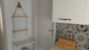 A kitchen with white cabinets, a wooden crate on the countertop, and a decorative wall with patterned tiles. - Panoramic Costa Rei (MURAVERA CA)