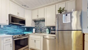 Una cocina moderna con armarios blancos, electrodomésticos de acero inoxidable y un backsplash de azulejos azules.