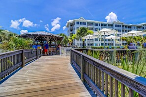 A wooden boardwalk leading to a resort with multiple balconies and umbrellas. - Oceanfront condo with pools, hot tubs, fitness room, & central AC (Hilton Head)