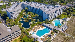 Un gran hotel con varias edificaciones, una piscina central y zonas ajardinadas aledañas.