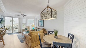 Amplia sala de estar con mesa de comedor, sillas, sofá y ventilador de techo.