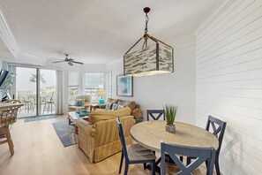 A spacious living area with a dining table, chairs, a sofa, and a ceiling fan. - Oceanfront condo with pools, hot tubs, fitness room, & central AC (Hilton Head)