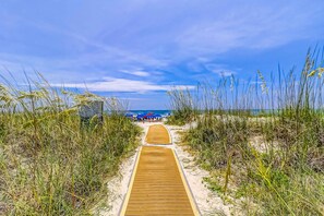 A wooden pathway leading to a beach area with dunes and a clear sky. - Oceanfront condo with pools, hot tubs, fitness room, & central AC (Hilton Head)