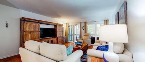 Una sala de estar con sofá, televisión, mueble de madera y lámpara.