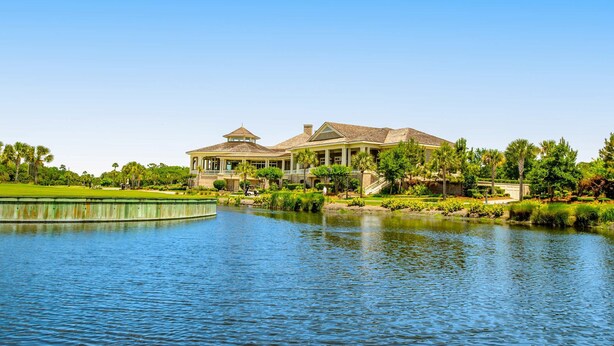 A large house with a pool, surrounded by greenery and palm trees. - Coastal resort style villa with pool, golf, & balcony  WD, AC, & dog friendly (Hilton Head)