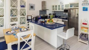 Een moderne keuken met witte kasten, een blauw aanrecht en een roestvrijstalen koelkast.