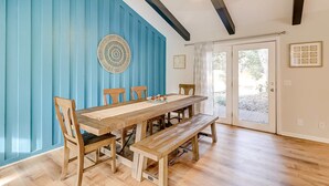 A dining area with a wooden table, benches, and chairs, a blue accent wall, and a ceiling fan. - 3 bedroom home Palm lined hideaway with pool and Dog Friendly (Hilton Head)
