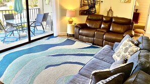 Ein Wohnzimmer mit einer Couch, einem Couchtisch, einer Lampe und Blick durch eine Glasschiebetür auf eine Außenpatio.
