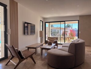 Ein modernes Wohnzimmer mit einer Couch, einem Sessel, einem Tisch und einem Fernseher.