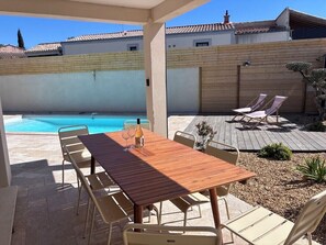 Un porxo cobert amb piscina, terrassa de fusta i gandules.