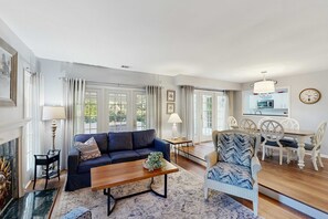 A living room with a sofa, coffee table, and a dining area with chairs and a table. - Renovated Dog Friendly Villa with Patio & Pool  Near Golf & Beach (Hilton Head)