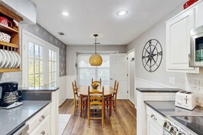 A kitchen with a dining table, chairs, a coffee maker, a toaster, and a wall clock. - Renovated Dog Friendly Villa with Patio & Pool  Near Golf & Beach (Hilton Head)