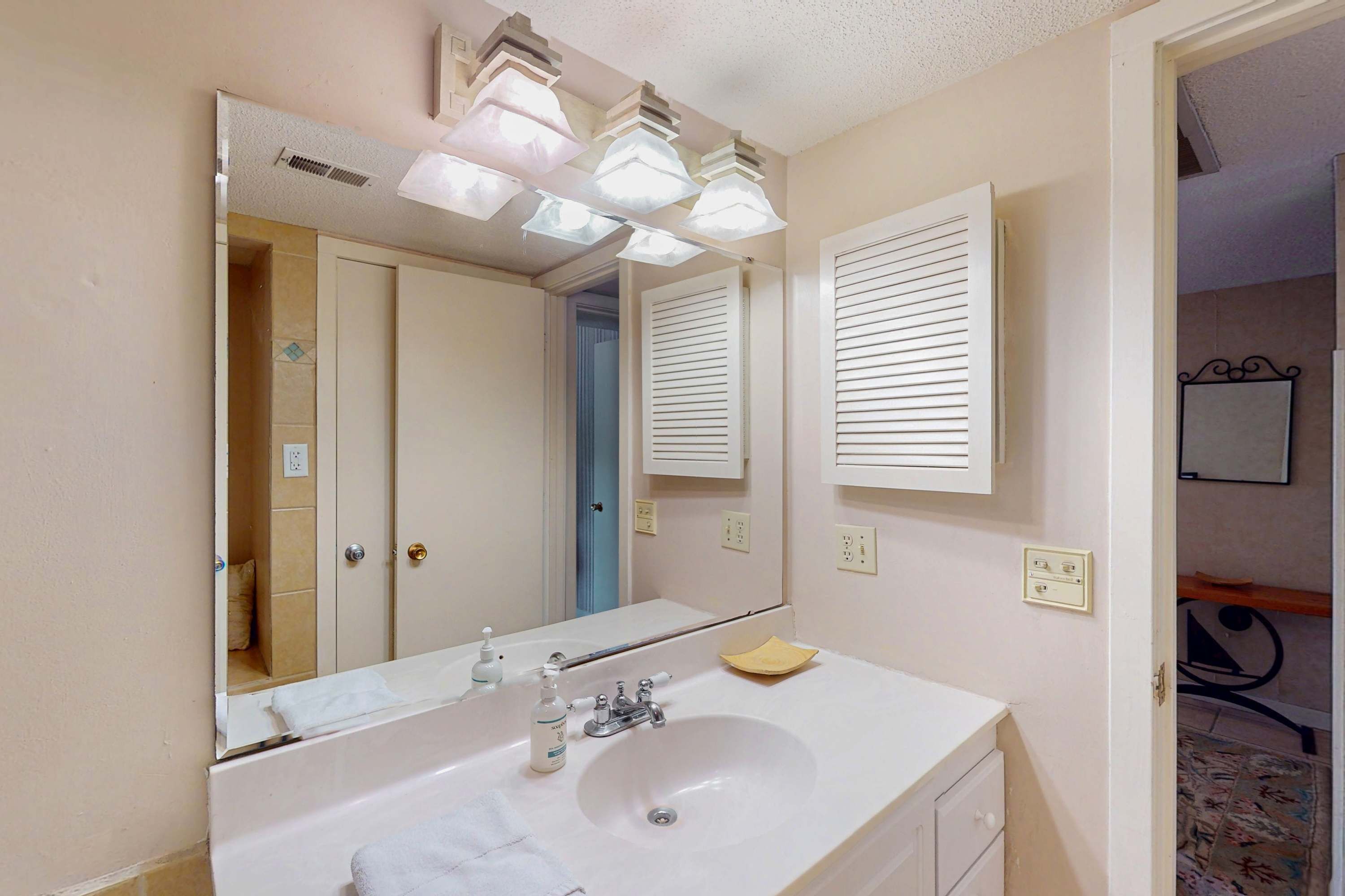 A bathroom with a white sink, mirror, and overhead lights.