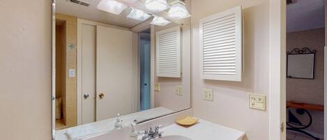 A bathroom with a white sink, mirror, and overhead lights.