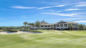 Un campo de golf con una casa grande al fondo.
