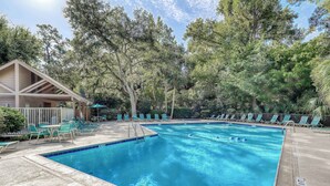 Una piscina con sillas de descanso y una zona de estar cubierta.