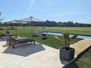 Ein Poolbereich mit Liegestühlen, einer Pergola und Blick auf die umliegende Landschaft.