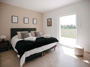 Ein Schlafzimmer mit einem Bett, Nachttischen, einem Fenster und gerahmten Bildern an der Wand.