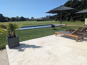 A poolside area with a pool, lounge chairs, and umbrellas. - Marcel's House - Private Pool (Althen-des-Paluds)