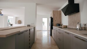 Una cocina moderna con una isla central, armarios grises y un amplio ventanal.