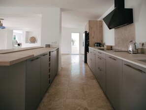 Eine moderne Küche mit einer zentralen Kochinsel, grauen Schränken und einem großen Fenster.