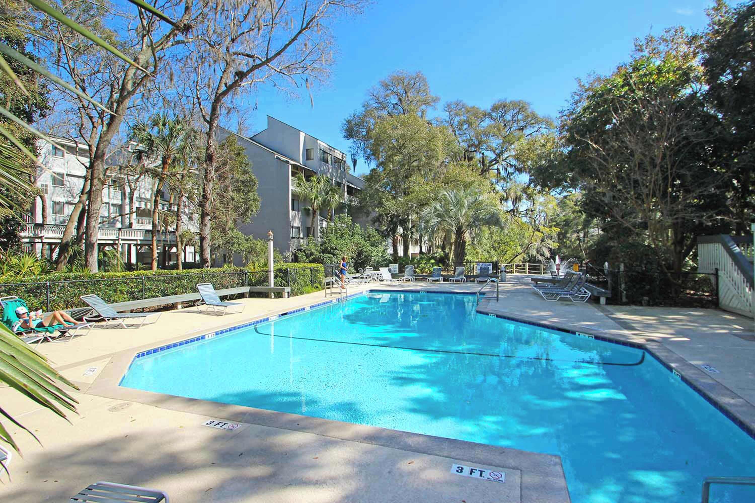 A swimming pool with lounge chairs and a building in the background.