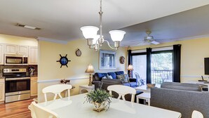 Una cocina moderna con comedor, una sala de estar con sofá y televisión, y un ventilador de techo.