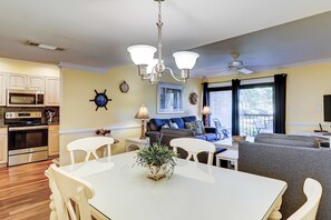 Eine moderne Küche mit Essbereich, ein Wohnzimmer mit Sofa und Fernseher sowie ein Deckenventilator.