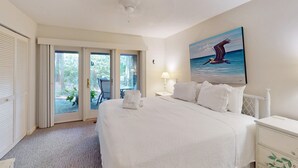 A hotel room with a bed, a painting of a bird, a window, and a door. - Lovely house with gourmet kitchen, screened porch, & open deck (Hilton Head)