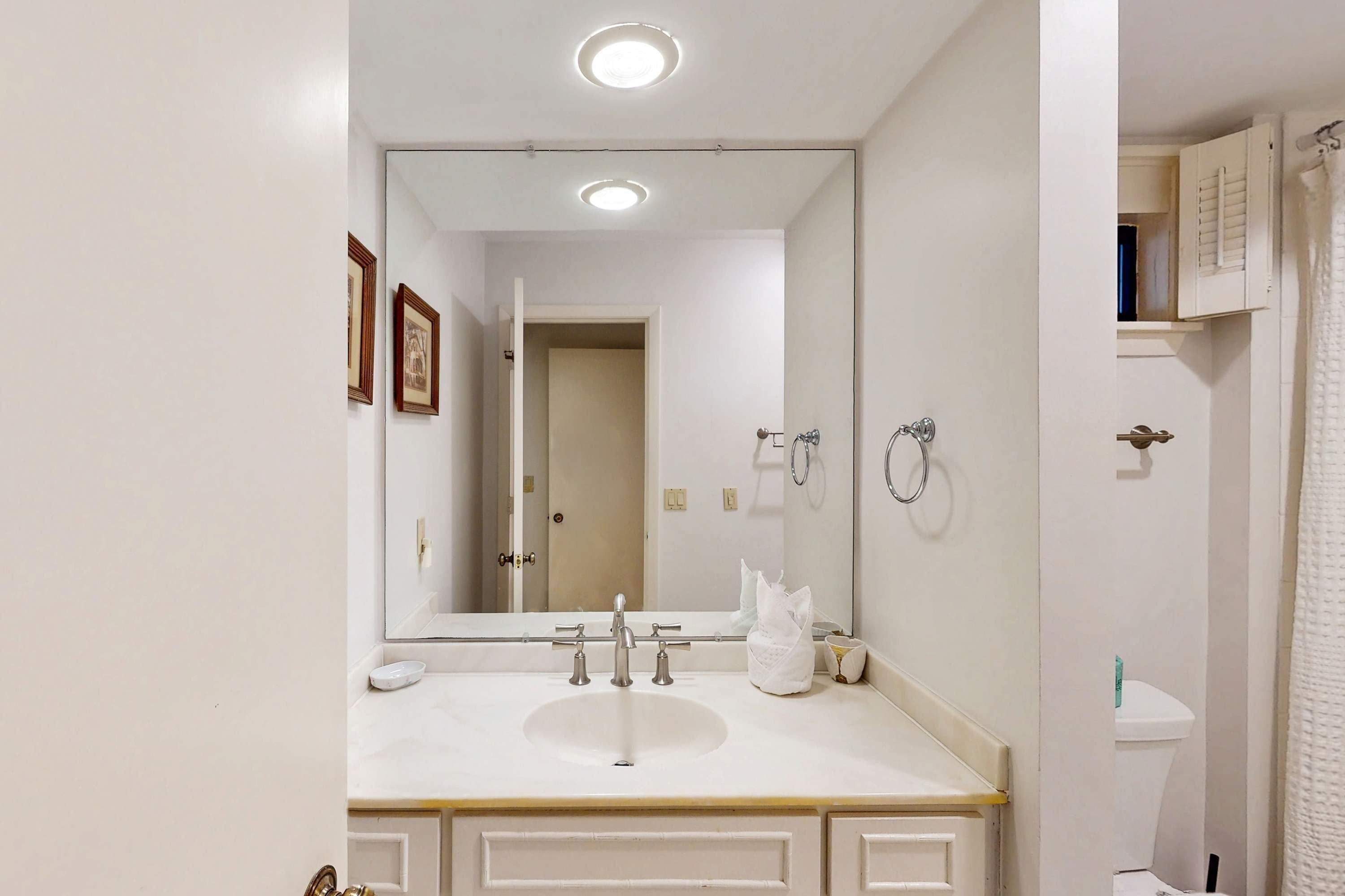 A bathroom with a white sink, mirror, and a toilet.