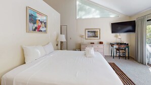 A hotel room with a large bed, a desk with a chair, a television, and artwork on the walls. - Lovely house with gourmet kitchen, screened porch, & open deck (Hilton Head)