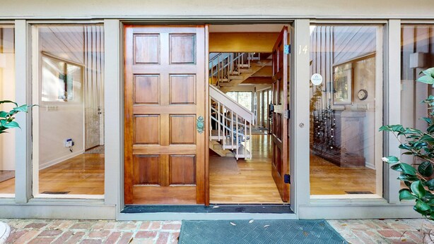 A wooden door with a glass panel, a staircase, and a brick wall. - Lovely house with gourmet kitchen, screened porch, & open deck (Hilton Head)