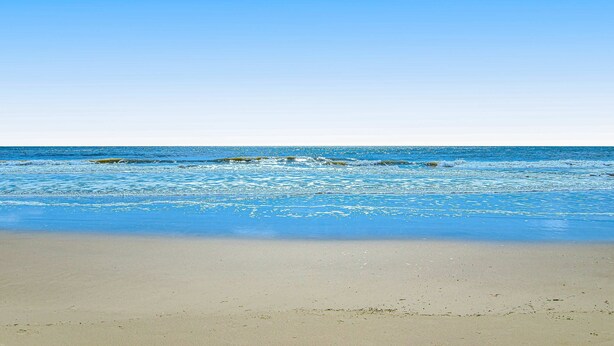 Ein Strand mit klarem, blauem Wasser und sandigem Ufer.
